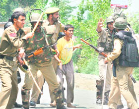 Security forces arrest a boy during a protest against the alleged gang-rape of a woman, in Kulgam