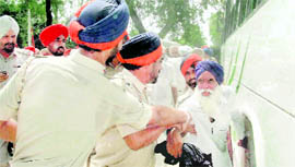 Policemen drag an agitating farmer and bundle him off into a bus after he resisted the forcible possession of land in Gobindpura on Saturday.