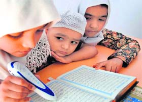 A girl reads the holy Quran with a pen made in China at a book store at Purani Haveli in Hyderabad on Sunday
