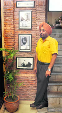 Brig SS Gill (retd) posing with photographs of Flt Lt Nirmaljit Singh Sekhon at his restaurant. 