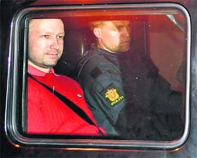 Bomb and terror suspect Anders Behring Breivik (in red) leaves the courthouse in a police car in Oslo on Monday, after the hearing to decide his further detention
