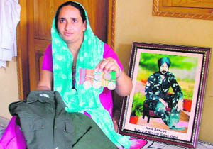 Jaswinder Kaur, widow of Lance Naik Nirmal Singh, shows his uniform and medals at Johlan village. 