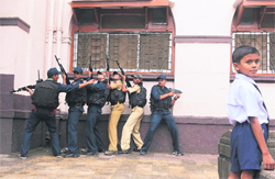 A schoolboy (R) looks on as personnel from the Mumbai Police Commando unit take part in a mock drill at St Michael High School in Mumbai on Tuesday. The drill was conducted by the Mumbai Police Quick Response Team following the July 13 triple bomb blasts in the city
