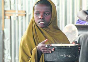 An internally displaced Somali girl carries a pot of rice at the government-run Badbaado refugee camp in a suburb of Mogadishu on Tuesday