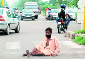 A beggar endangers his life as he drags himself to cross the road during rush hour in Chandigarh.