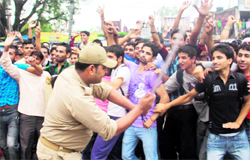 A policeman tries to disperse youths protesting outside the BSF Frontier Headquarters in Jammu on Thursday