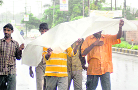 Labourers protect themselves from rain in Dehradun on Sunday evening.