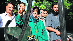 PDP chief Mehbooba Mufti is seen through a locked gate after being prevented by the police from going to Sopore in Srinagar on Sunday. 