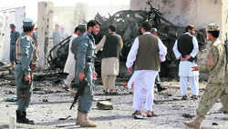 Afghan police officers gather near a wrecked police vehicle at the entrance of the police headquarters in Lashkar Gah on Sunday