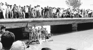 People watch the rescue work after a private bus fell into the Barna river after the driver lost control over the vehicle in Raisen district of Madhya Pradesh 