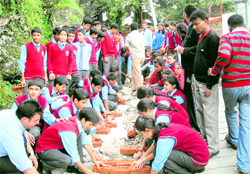 Students of Manav Bharti International School fill up a dug-up road near their institution in Mussoorie on Tuesday