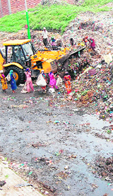 A JCB machine tries to keep garbage off the road at Bhagatwala in Amritsar. 