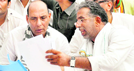 BJP leader Rajnath Singh discusses a point with Haryana BJP president Krishan Pal Gurjar at Ghata village in Gurgaon district on Friday.