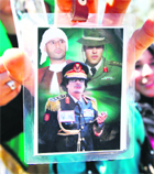 Khamis Gaddafi (R) is seen alongside his father Libyan leader Muammar Gaddafi (C) and brother Saif al-Islam (L) in a picture held by a student near a building in Tripoli.