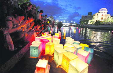 People pray after releasing paper lanterns in a river facing the gutted Atomic Bomb Dome in remembrance of atomic bomb victims on the 66th anniversary of the bombing in Hiroshima 