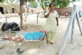 Gurnam Kaur stands behind the barbed wire fencing outside her house at Gobindpura village in Mansa
