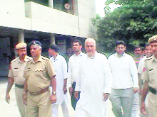 Roshan Lal Arya (second from right) and his son come out of a court at Yamunanagar on Sunday while in custody of the Faridabad police.