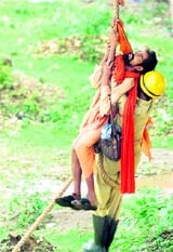 A Fire Brigade employee rescues a trapped sadhu in Jammu on Sunday.