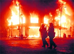 Policemen look on as fire rages through a building in Tottenham on Sunday