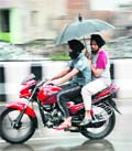 Youths on a bike try to escape the showers in Bathinda