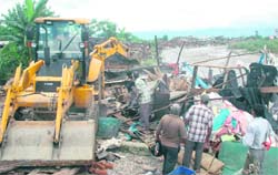 A JCB vehicle of the Dehradun Municipal Corporation demolishes illegal structures in the Ram Nagar area in Dehradun on Wednesday