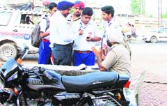 Traffic police personnel check documents of a two-wheeler of a student