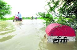People wade through a flooded road after water levels of the Ganga and the Yamuna rose following a heavy downpour near Allahabad on Wednesday