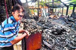 Azim Mohamed, owner of a cutlery hire company, looks at the charred remains of his goods after his store was set ablaze in north London on Wednesday