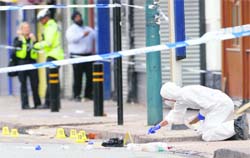 A police forensic officer inspects the site where three men were killed by a car in the Winson Green area of Birmingham on Wednesday