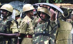 Riot police personnel use their shields to protect themselves from rain during a protest by the BJP in New Delhi 