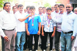 DIPRO Jagdeep Duhan (right) and wrestling coach Raj Singh Chhikara congratulate Praveen and Sandeep by offering them sweets at Sonepat. 