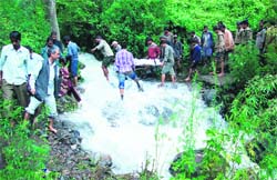 The body of one of the cloudburst victims is carried through difficult terrain.