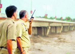 Policemen stand guard on the banks of the Tawi, as heavy rain triggered flash floods in the Jammu region on Friday