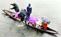 People carrying umbrellas ride a boat as it rains in Srinagar on Friday