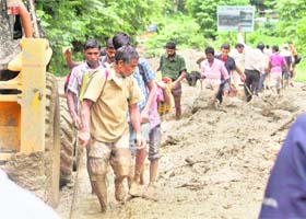 Commuters walk through a landslide site on a highway in Chumukediam in Nagaland on Saturday