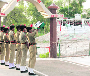 BSF soldiers hold the Tricolour during the Retreat ceremony at the Sadqi border post