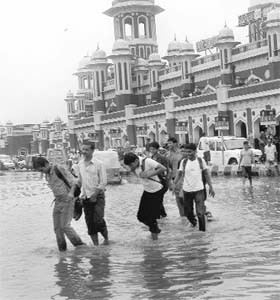 People wade through rain water outside the Charbagh railway station in Lucknow on Sunday