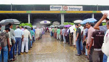 Delhi Metro commuters queue up in rain for security check at the Seelampur Metro station in New Delhi 