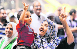 A woman gestures while holding a child during a pro-Gaddafi rally in Tripoli. 