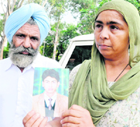 Balwinder Singh and Gurvinder Kaur hold a picture of their son Gagandeep Singh at the Police Headquarters in Sector 9 of Chandigarh on Thursday