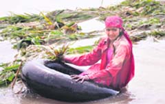 a woman uses a tyre tube to reach her house in Chhota Gang Daspur village in Haridwar