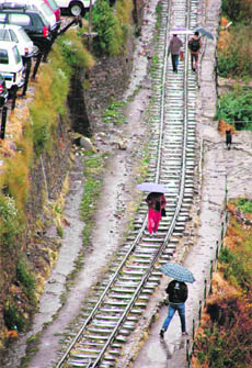 People walk on a railway track during rain in Shimla 