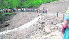 People try to get to the other side of a road covered with debris near Bhawali on Friday.