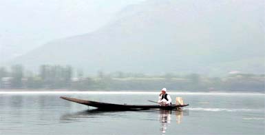 A man rows a boat across the Dal Lake on a foggy morning in Srinagar.