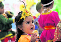 A school child dressed as Lord Krishna has a snack in Ludhiana on Friday