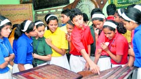 School students look at the Holy Koran engraved on wood at an exhibition in Dehradun on Saturday.
