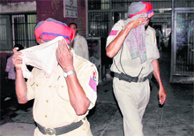 Sukhwant Singh and Tirlochan Singh, attached with the PCR motorcycle patrol, hide their faces after being caught at a liquor vend in Ludhiana on Friday night. Their blood samples have been sent to the laboratory to establish if they had consumed liquor. 