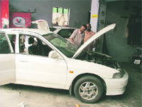 A mechanic fixes a car that got damaged due to rain at a workshop in Ludhiana. 