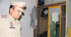 A police official inspects a cupboard where the suspected robbery took place in Ludhiana on Saturday.