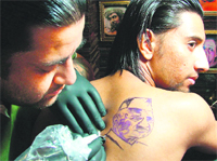 A supporter gets a tattoo of Anna Hazare made on his back